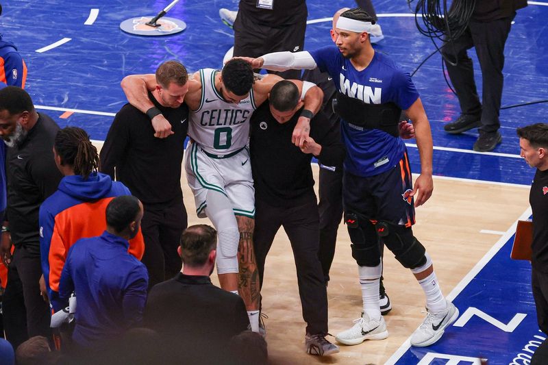 May 12, 2025; New York, New York, USA; Boston Celtics forward Jayson Tatum (0) is helped off the court by after an injury in the second half during game four of the second round for the 2025 NBA Playoffs as New York Knicks guard Josh Hart (3) gestures at Madison Square Garden. Tatum would leave the game with an injury after this play. Mandatory Credit: Vincent Carchietta-Imagn Images