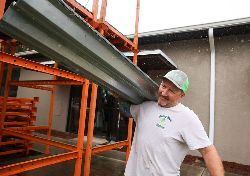 Richard Dubord, of Port St. Lucie, carries free metal shutters to his truck at O' Donnell Impact Windows & Storm Protection on Tuesday, Oct. 8, 2024, at 1740 N.W. U.S. 1 in Stuart. "These are all recycled panels we get from jobs," said owner Mike O'Donnell. "We hold on to these for a year or two until there's a bad storm .... we put these panels out to the public because a lot of people can't get plywood or last minute hurricane protection." They will be open until 4 p.m. but the owner said if there is a steady flow of people they would stay open longer.