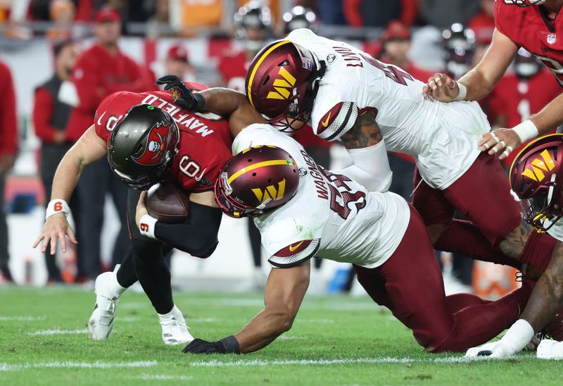Jan 12, 2025; Tampa, Florida, USA; Tampa Bay Buccaneers quarterback Baker Mayfield (6) is tackled by Washington Commanders linebacker Bobby Wagner (54) and linebacker Dante Fowler Jr. (6) during the fourth quarter of a NFC wild card playoff at Raymond James Stadium. Mandatory Credit: Kim Klement Neitzel-Imagn Images