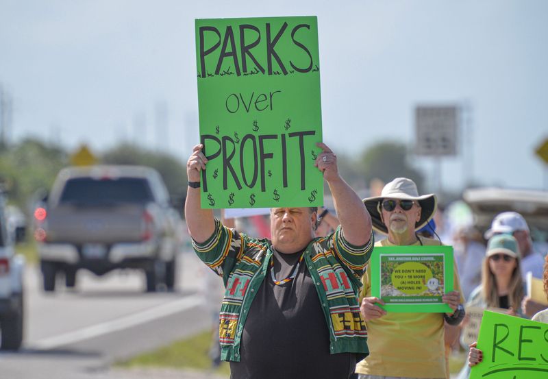 Gary Wilcox (front), of Miami, participates in a protest at the entrance of Jonathan Dickinson State Park on Saturday, April 5, 2025, in Hobe Sound. Rallies, billed as a State Park Lovefest, were planned Saturday at 16 state parks around Florida -- also including Fort Pierce Inlet State Park on the Treasure Coast -- as part of a statewide effort to protect state parks. Jonathan Dickinson is about a 20-minute drive from President Donald Trump's Jupiter golf club. Senate Bill 80, the State Park Preservation Act, filed by state Sen. Gayle Harrell, R-Stuart, would place strict limitations on development in state parks as well as outdoor activities that can be promoted at the parks such as golf, tennis, pickleball and other sports requiring a ball field.