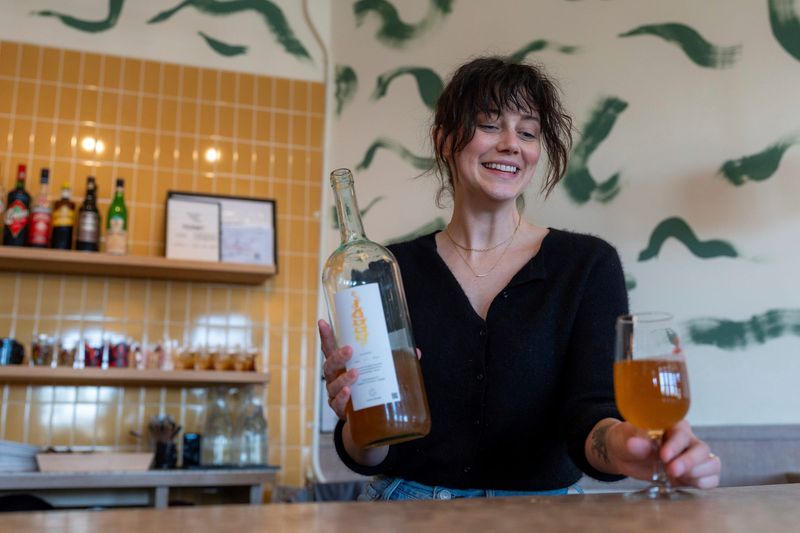 Symantha Duggan, co-owner of Vesper Books and Wine, serves a glass of a Cantina Giardino white wine to a customer inside the wine bar in Detroit on Friday, March 21, 2025.