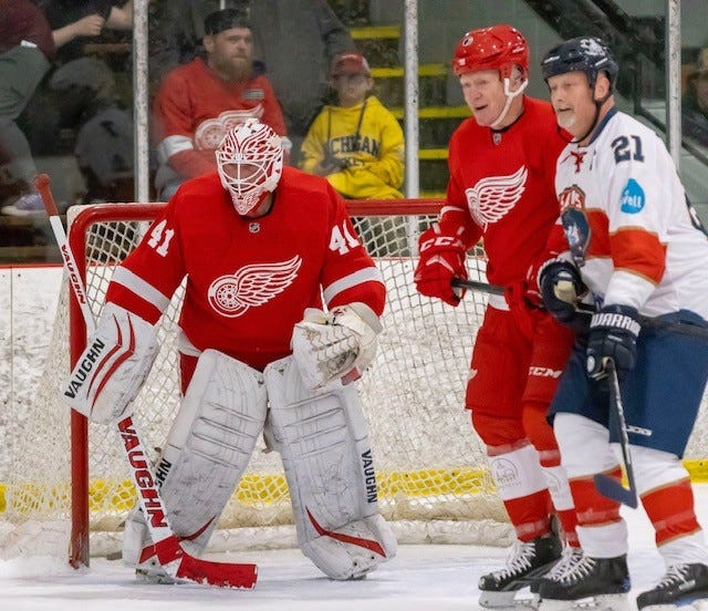 Former Detroit Red Wing Red Berenson defends Scott DesAutel of The Well Church in front of goalie Ed Mio during a past Red Wings alumni game.