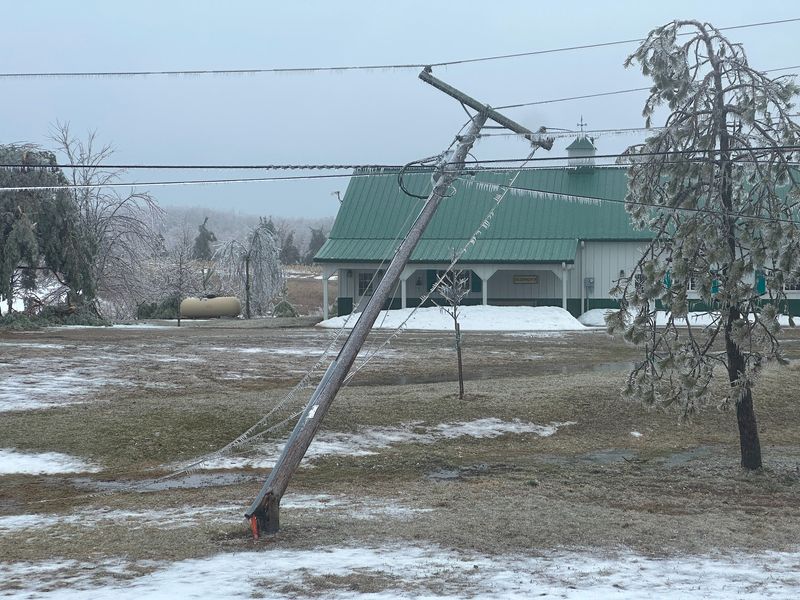 A power pole leans precariously, its top twisted and tangled in utility lines, after succumbing to the weight of heavy ice on March 30 just south of Charlevoix County near Friske’s Farm Market.