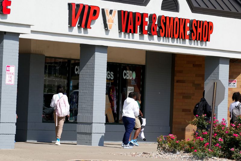 Teens walk by a vape and smoke shop across the street from Winton Woods High School along Kemper Road, Tuesday, Sept. 26, 2023, in Forest Park, Ohio.