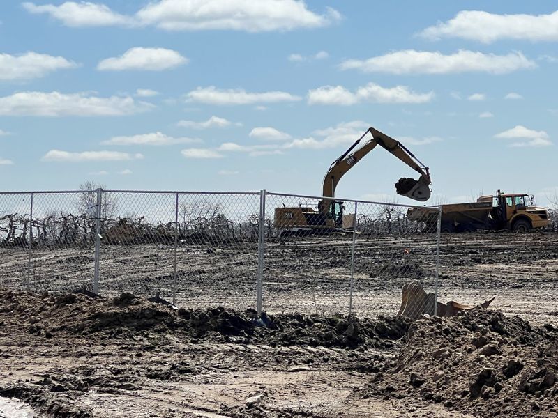 Construction workers use a backhoe on property on the south side of Silver Lake Road, adjacent to Blake's Farm apple orchard, where 121 homes will be built in the Orchard Crossing Estates development.