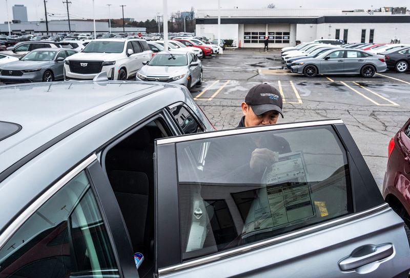 Car salesman Allan Luu removes the window sticker from a 2025 Honda CRV while getting the new vehicle ready for his client at Tamaroff Honda in Southfield on Thursday, April 10, 2025.