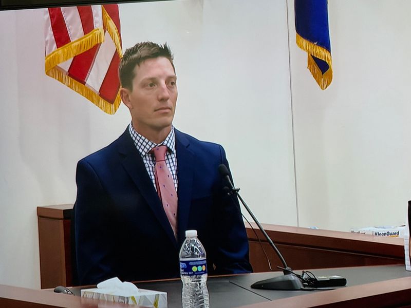 The media room display shows Christopher Schurr taking the stand to testify in 17th Circuit Court on Friday, May 2, 2025, in Grand Rapids, Mich. Schurr, 34, is charged with second-degree murder stemming from the April 2022 fatal shooting of Patrick Lyoya.