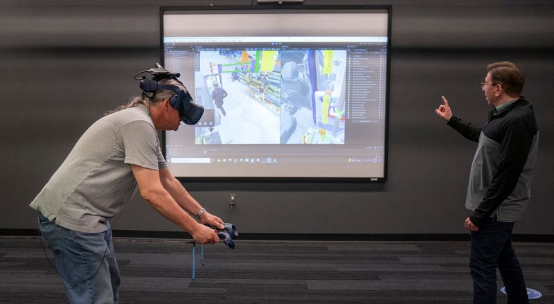 Detroit Free Press autos writer Eric Lawrence, left, uses a virtual reality headset and controllers to replicate the motion of putting a door on its hinges with the guidance of Virtual Reality Design Review Specialist Joe Dzwonkowski, right, during a Stellantis demonstration at the company’s VR lab in Auburn Hills on Thursday, May 8, 2025.