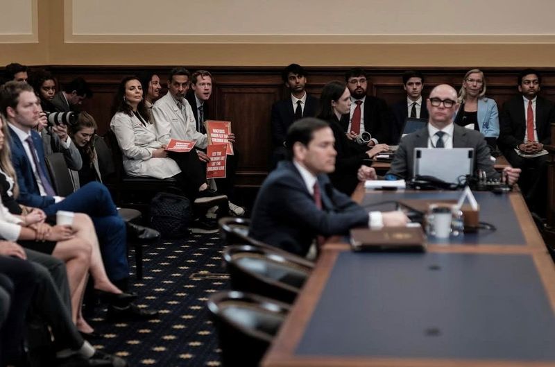 Dr. Nidal Jboor and Dr. Karameh Hwash-Kuemmerie, co-founders of an international group called Doctors Against Genocide, hold signs in the U.S. Senate gallery during U.S. Secretary of State Marco Rubio testifies to the Senate Committee on Foreign Relations on May 21, 2025.