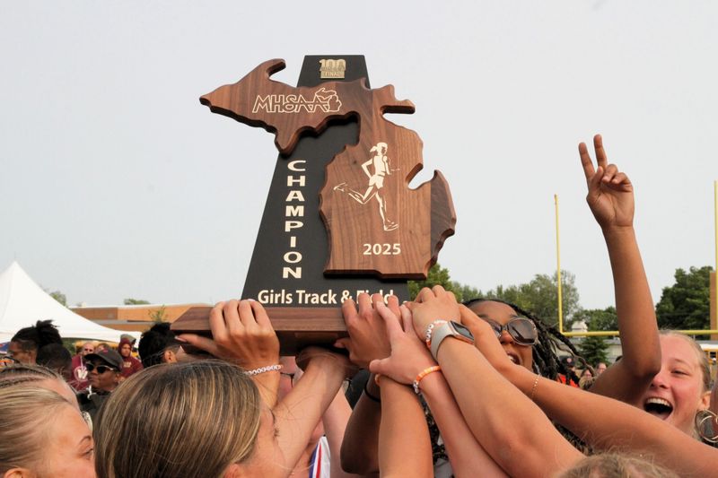 Members of the Sturgis girls track program react with the team state championship trophy in Hamilton on Saturday.