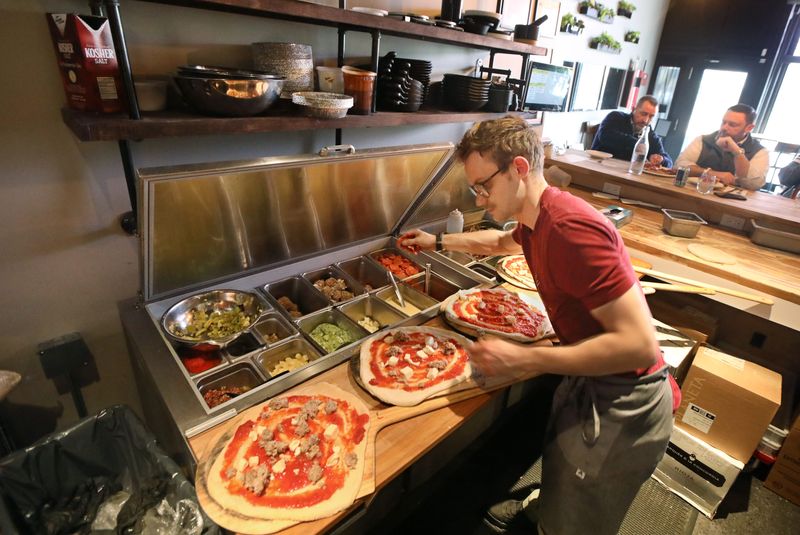 Owner and chef Kody Derhak works on a row of pizzas during the lunch-hour rush at Ardor Park Artisanal Pizza.