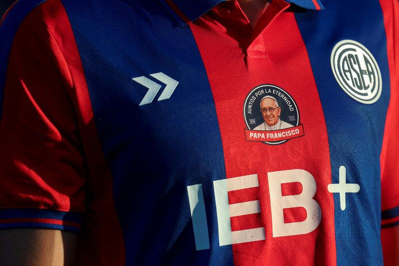 A view shows a shirt of the San Lorenzo de Almagro, Pope Francis' hometown soccer team, with a badge with an image of him and a message reading "together for eternity", on the day of an Argentine first division match against Rosario Central, following the death of the pontiff, at the Pedro Bidegain stadium, in Buenos Aires, Argentina, April 26, 2025. REUTERS/Cristina Sille