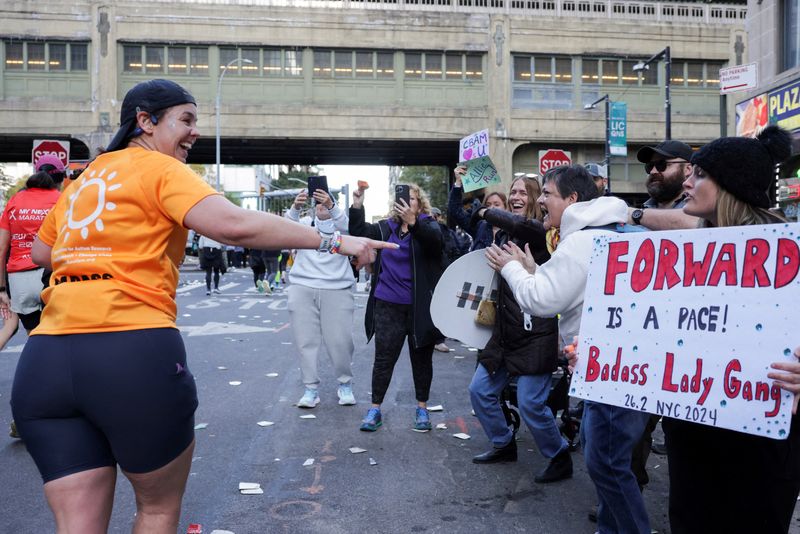 FILE PHOTO: A competitor points at a sign in the Queens borough during the 2024 TCS New York City Marathon, in New York City, U.S., November 3, 2024. REUTERS/Kent J Edwards/File Photo