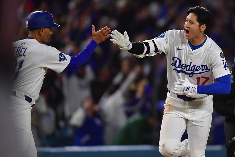 Apr 2, 2025; Los Angeles, California, USA; Los Angeles Dodgers designated hitter Shohei Ohtani (17) is greeted by third base coach Dino Ebel (91) after hitting a walk off solo home run against the Atlanta Braves during the ninth inning at Dodger Stadium. Mandatory Credit: Gary A. Vasquez-Imagn Images