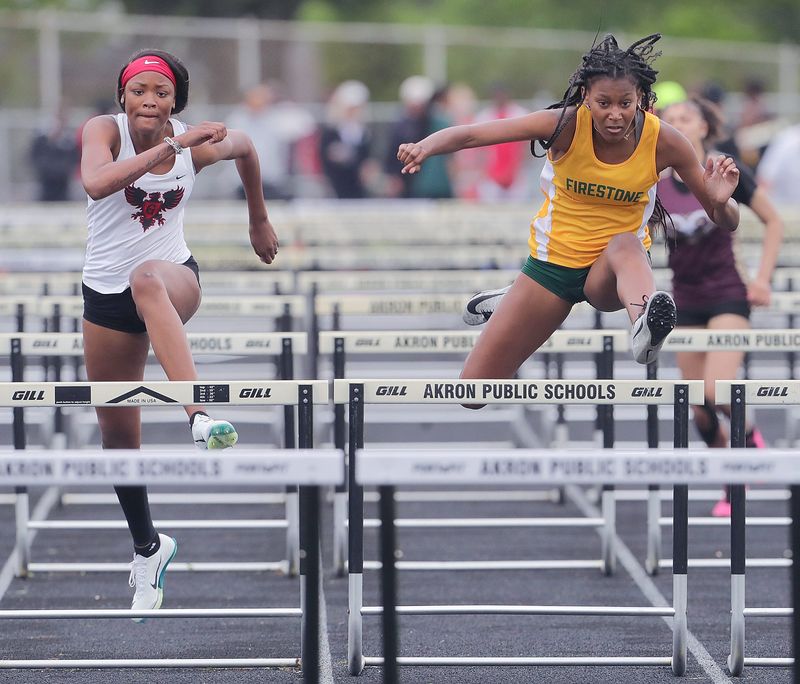Buchtel’s Akaliya White, left, and Firestone’s Mariah Richards head for the finish line in the 100-meter hurdles at the City Series track and field championships May 17, 2025, in Akron, Ohio.