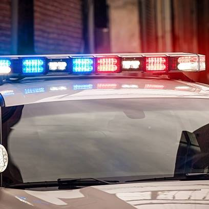 Sirens are shown flashing on a police car in transit.