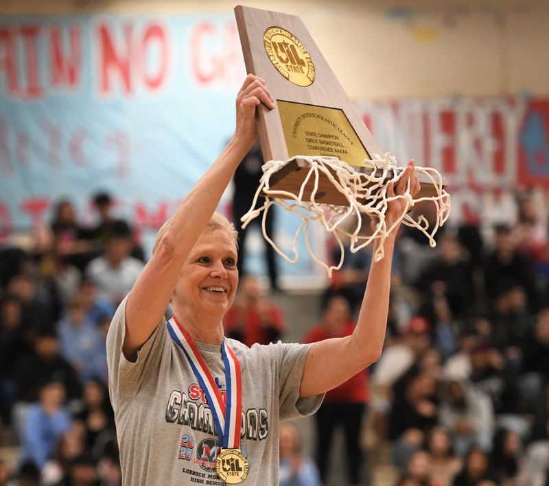 Monterey girls basketball coach Jill Schneider lifts the team's state championship trophy at a pep rally Wednesday, March 5, 2025, at Monterey High School.