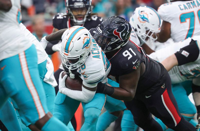 Dec 15, 2024; Houston, Texas, USA; Houston Texans defensive tackle Folorunso Fatukasi (91) attempts to tackle Miami Dolphins running back De'Von Achane (28) during the first quarter at NRG Stadium. Mandatory Credit: Troy Taormina-Imagn Images