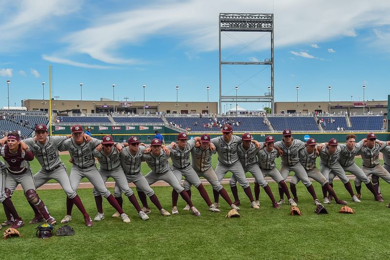 Jun 21, 2022; Omaha, NE, USA; Texas A&M Aggies players celebrate the win by "sawing 'em off" against the Notre Dame Fighting Irish after the game at Charles Schwab Field. Mandatory Credit: Steven Branscombe-USA TODAY Sports