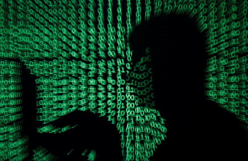 Man holds laptop computer as cyber code is projected on him in this illustration picture