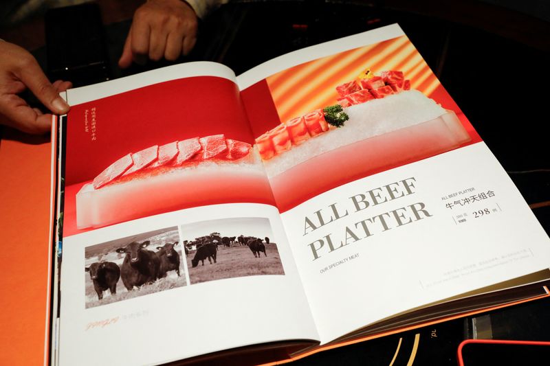 FILE PHOTO: Zhong Dingming, the manager of Jingli hotpot, shows part of the U.S. beef selection on the restaurant’s menu, in Beijing