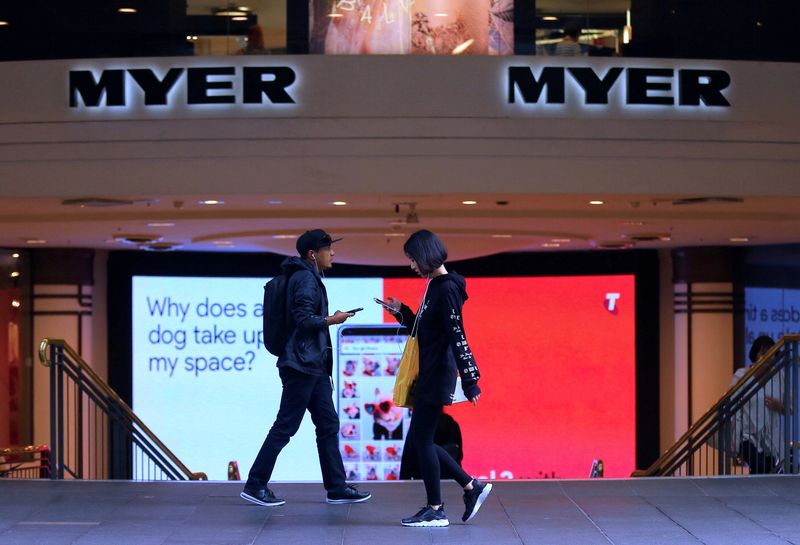 FILE PHOTO: Shoppers use their phones as they walk past the entrance to a Myer department store in Sydney
