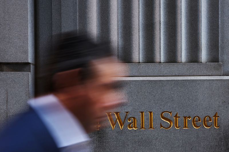 FILE PHOTO: A man walks past a Wall Street marking outside the New York Stock Exchange (NYSE) building on Tuesday following Monday’s broad sell off in New York City, U.S., March 11, 2025. REUTERS/Shannon Stapleton/File Photo
