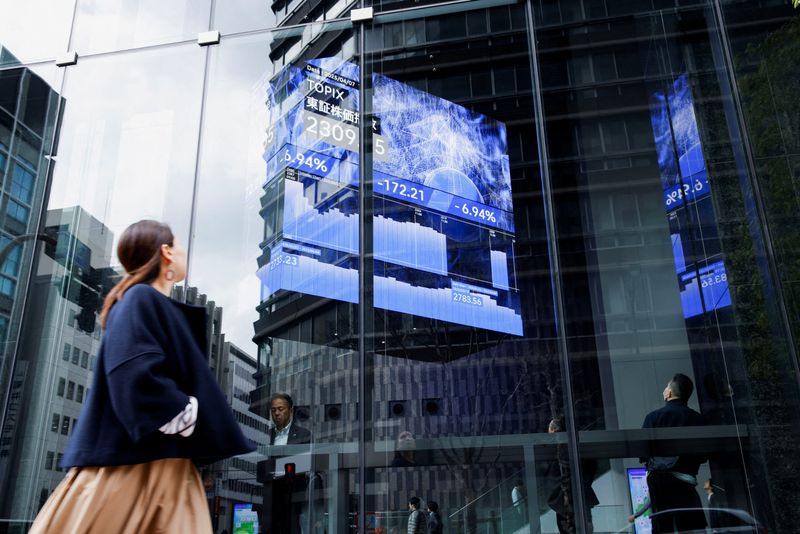 FILE PHOTO: A woman walks past a stock quotation board at a brokerage in Tokyo, Japan, April 7, 2025. REUTERS/Androniki Christodoulou/File photo