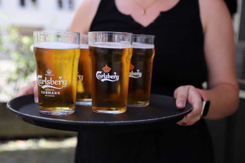 FILE PHOTO: A bar worker carries a tray of Carlsberg beer in Copenhagen, Denmark, July 30, 2022. REUTERS/Andrew Kelly/File photo