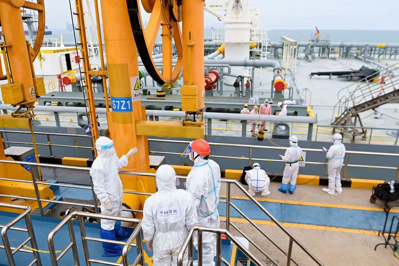 FILE PHOTO: Immigration inspection officers in protective suits check a tanker carrying imported crude oil at the port in Qingdao, Shandong province, China May 9, 2022. China Daily via REUTERS./File Photo