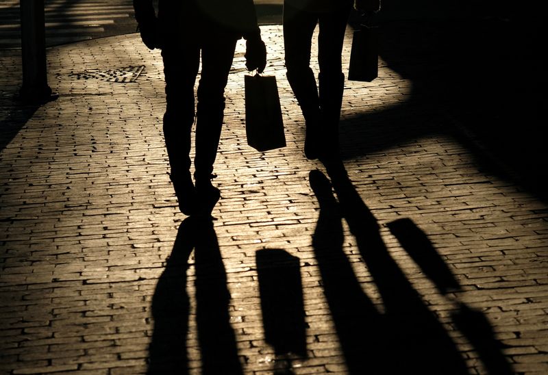 FILE PHOTO: Shoppers cast shadows as they carry their bags along the waterfront in Portland, Maine, U.S, December 26, 2024.  REUTERS/Kevin Lamarque/File photo