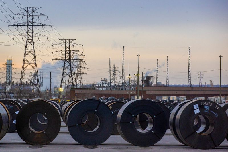 Coils of rolled steel sit in an industrial yard with transmission towers and smokestacks in the background at dusk in Hamilton, Ontario, Canada, January 27, 2025. REUTERS/Carlos Osorio/File Photo