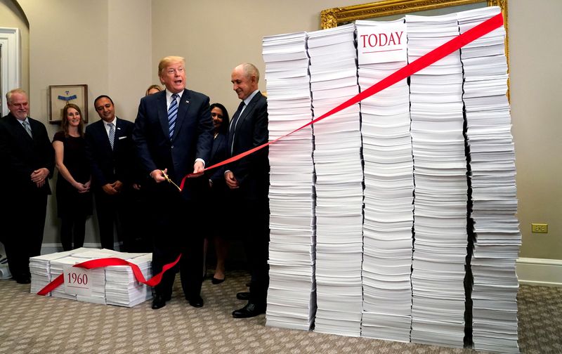 FILE PHOTO: U.S. President Donald Trump cuts a red tape while speaking about deregulation at the White House in Washington, U.S., December 14, 2017. REUTERS/Kevin Lamarque/File Photo
