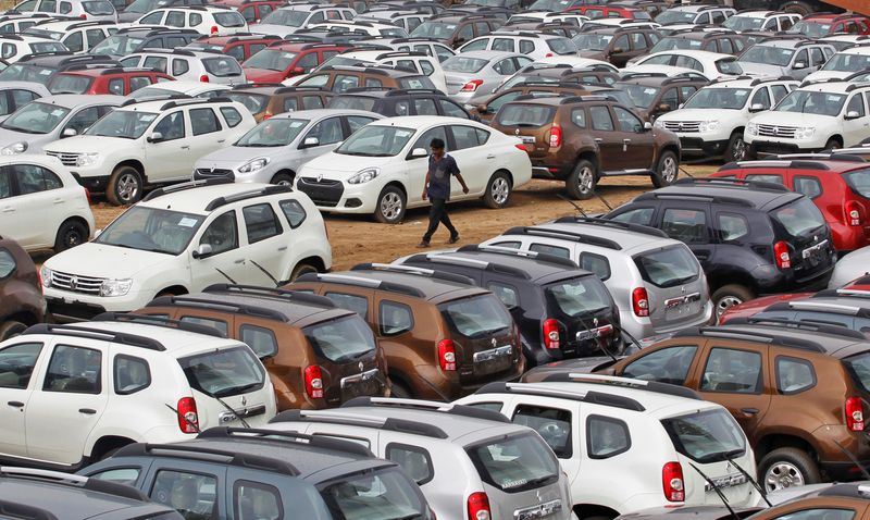 FILE PHOTO: A worker walks past parked Renault cars at its stockyard on the outskirts of the western Indian city of Ahmedabad June 11, 2013. REUTERS/Amit Dave/File Photo