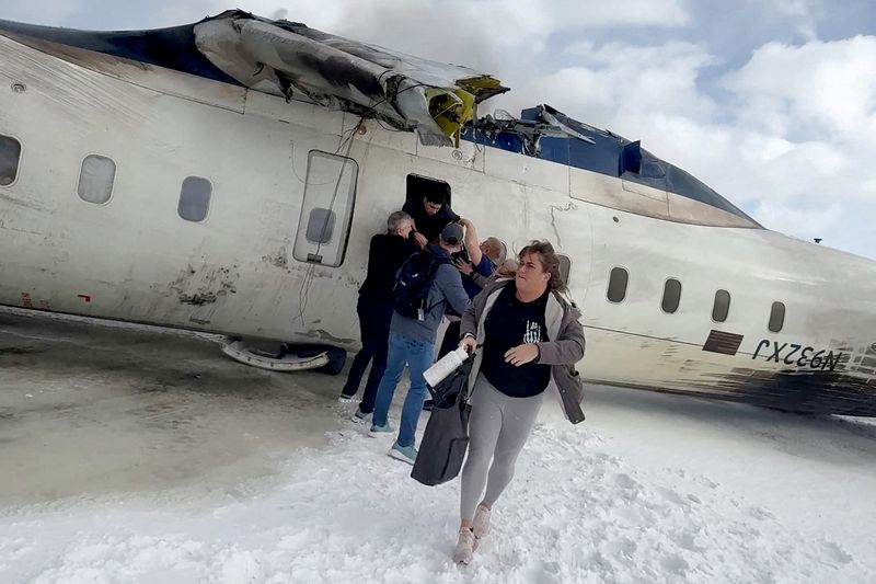 FILE PHOTO: Passengers leave a Delta Air Lines CRJ-900 jet after it crashed on landing at Toronto Pearson International Airport in Mississauga, Ontario, Canada February 17, 2025 in a still image from video.  Peter Koukov/Handout via REUTERS/File Photo