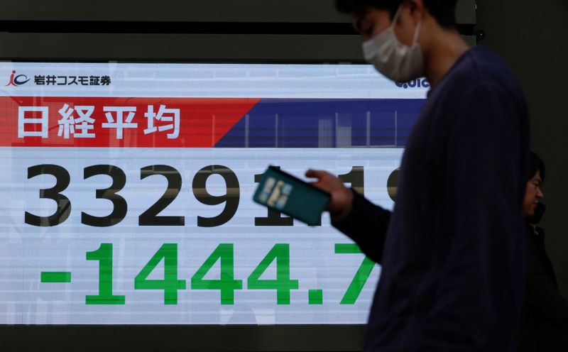 Pedestrians walk past a stock quotation board showing Nikkei share average outside a brokerage in Tokyo, Japan April 4, 2025. REUTERS/Kim Kyung-Hoon