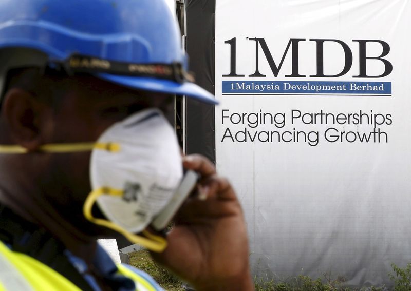 A construction worker talks on the phone in front of a 1Malaysia Development Berhad (1MDB) billboard at the Tun Razak Exchange development in Kuala Lumpur, Malaysia, February 3, 2016.   REUTERS/Olivia Harris/File Photo