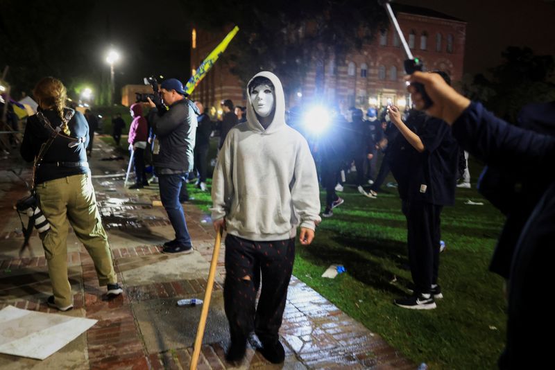 FILE PHOTO: A person wearing a mask stands as pro-Palestinian protesters face off with CHP officers near an encampment on the University of California, Los Angeles (UCLA) campus, amid the ongoing conflict between Israel and the Palestinian Islamist group Hamas, in Los Angeles, California, U.S., May 1, 2024. REUTERS/David Swanson/File photo