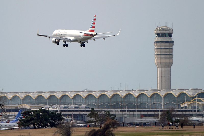 FILE PHOTO: An American Airlines Embraer ERJ-190AR airplane flies past the tower where air traffic controllers work at Reagan National Airport in Washington, U.S., January 12, 2019. REUTERS/Joshua Roberts/File Photo