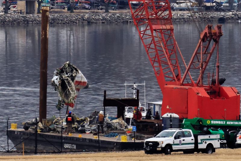 A barge carrying a crane move parts of the wreckage from the Potomac River, in the aftermath of the collision of American Eagle flight 5342 and a military Black Hawk helicopter that crashed into the river, by Ronald Reagan Washington National Airport, in Arlington, Virginia, U.S., February 5, 2025.  REUTERS/Eduardo Munoz/File Photo
