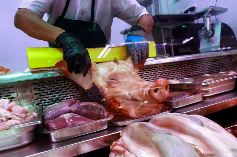 FILE PHOTO: A butcher handles a pork's head at a market stall in Madrid, Spain, June 17, 2024. REUTERS/Juan Medina/File Photo