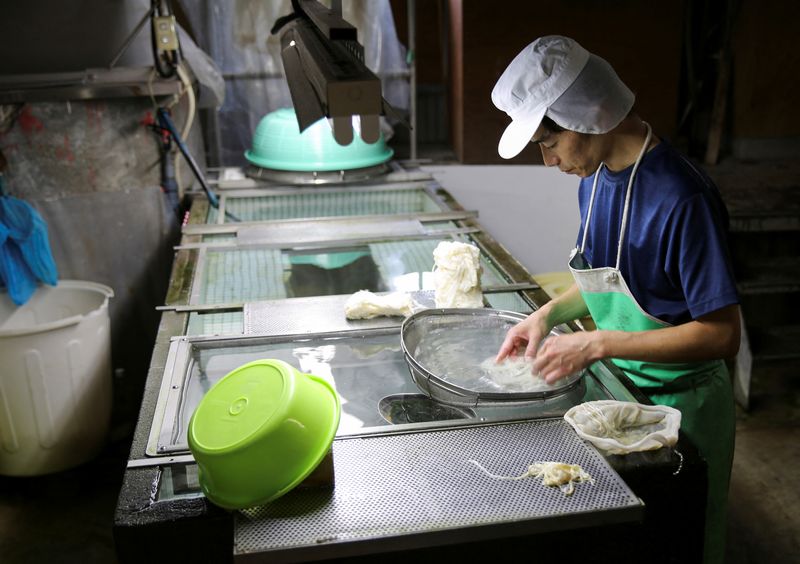 A worker removes impurities from raw paper materials at the Kashiki Seishi factory in Ino
