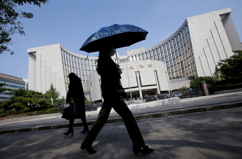 FILE PHOTO: People walk past the headquarters of the People's Bank of China (PBOC), the central bank, in Beijing, China September 28, 2018. REUTERS/Jason Lee/File Photo