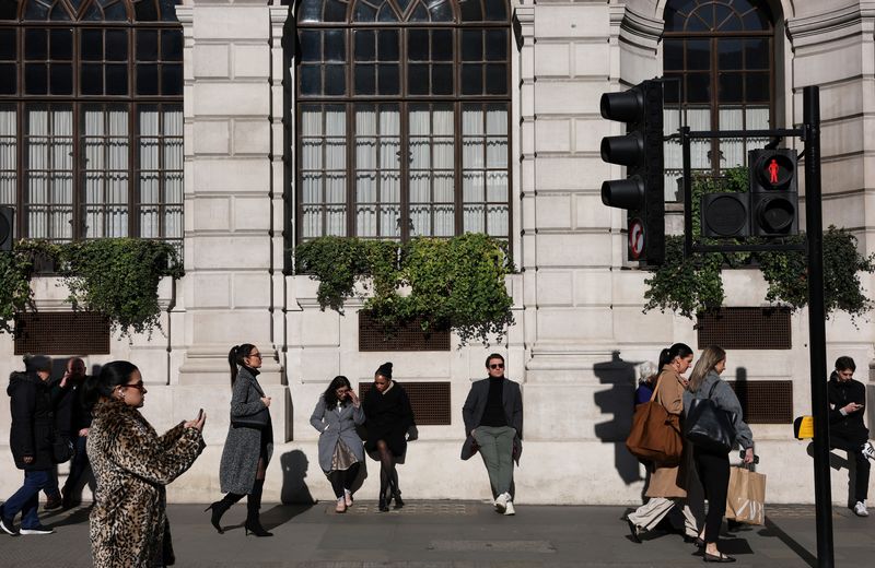 FILE PHOTO: People walk and relax in the sunshine in the City of London financial district in London, Britain, March 4, 2025. REUTERS/Toby Melville/File Photo