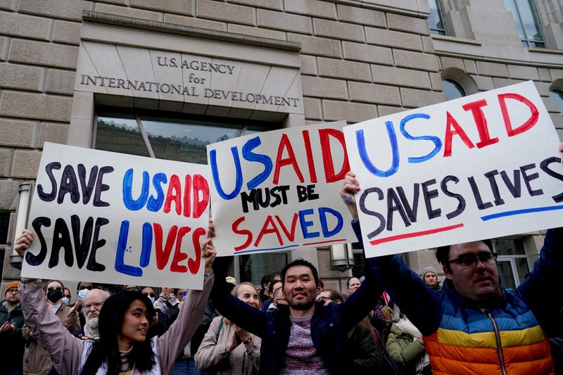 FILE PHOTO: People hold placards, as the USAID building sits closed to employees after a memo was issued advising agency personnel to work remotely, in Washington, D.C., U.S., February 3, 2025. REUTERS/Kent Nishimura/File Photo