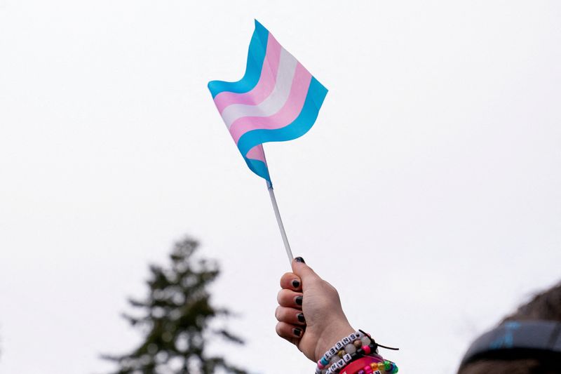 FILE PHOTO: A demonstrator holds a trans flag during a rally in support of trans youth in Seattle, Washington, U.S. February 8, 2025. REUTERS/David Ryder/File Photo