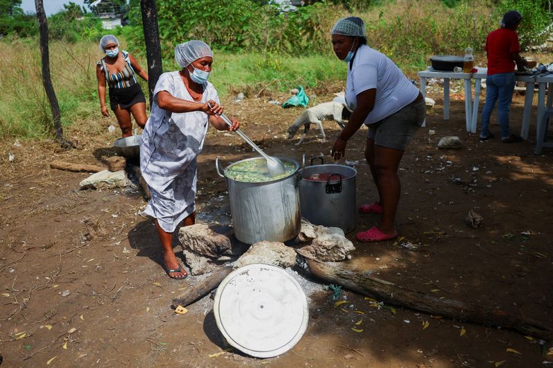 FILE PHOTO: People cook food during a visit by Charlotte Slente, Secretary General of the Danish Refugee Council (DRC), in Riohacha, Colombia December 2, 2024. REUTERS/Luisa Gonzalez/File Photo