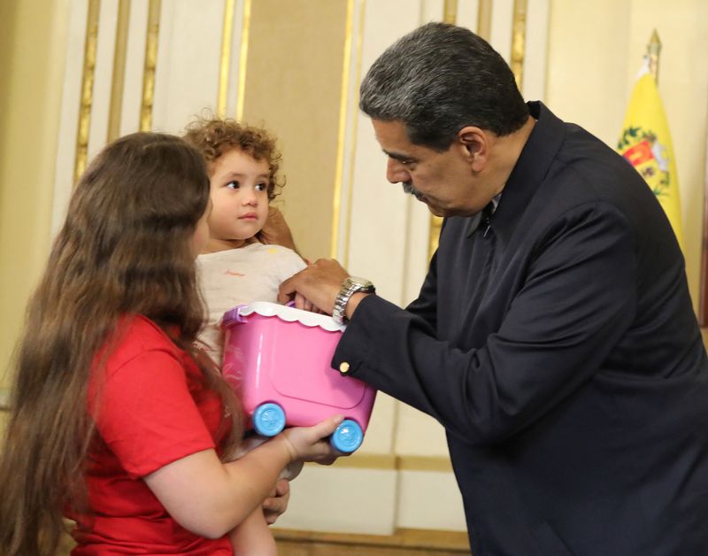 Venezuela's President Nicolas Maduro greets Maikelys Espinoza Bernal, a two-year-old from Venezuela who was separated from her parents, who is in the arms of her mother Yorely Bernal after being deported from the U.S., at Miraflores Palace, in Caracas, Venezuela May 14, 2025. Miraflores Palace/Handout via REUTERS