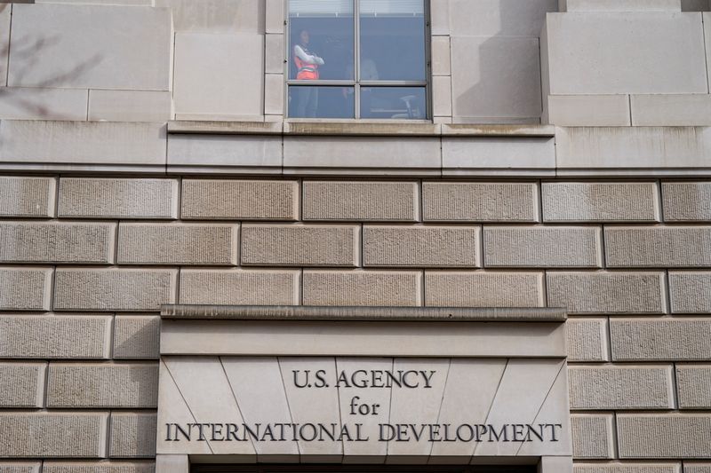 FILE PHOTO: A worker looks out of the window of the U.S. Agency for International Development (USAID) building in Washington, U.S., February 3, 2025. REUTERS/Kent Nishimura/File Photo
