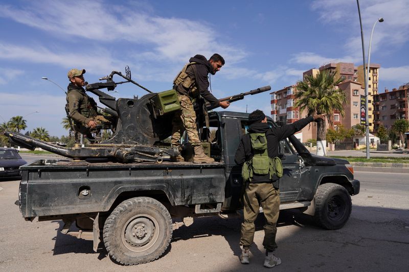 A member of Syrian forces stands on a military truck in Latakia
